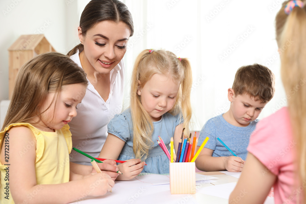 Little children with kindergarten teacher drawing at table indoors. Learning and playing Little children with kindergarten teacher drawing at table indoors. Learning and playing