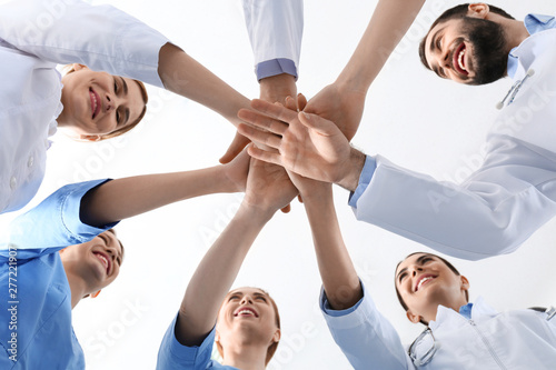 Team of medical doctors putting hands together on white background, closeup. Unity concept