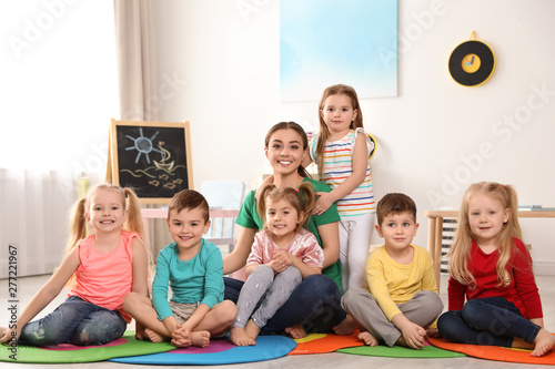 Kindergarten teacher with group of children in playroom. Indoor activity