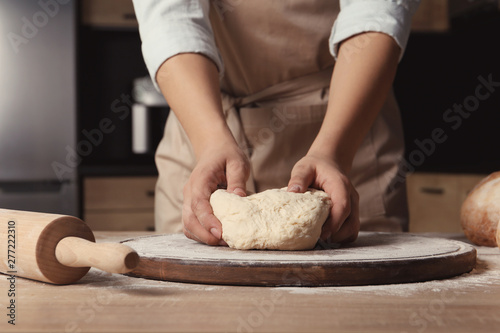 Female baker preparing bread dough at table, closeup