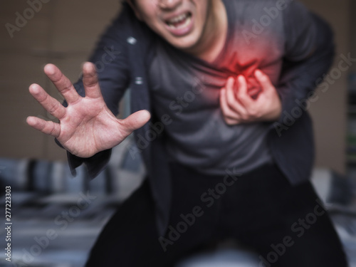 Severe heartache, man suffering from chest pain, having heart attack or painful cramps, pressing on chest with painful expression