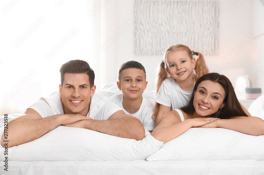 Portrait of happy family on large bed in room