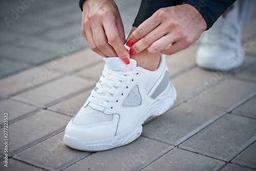 Woman get ready for run. Female hands tying shoelaces on a sport sneakers