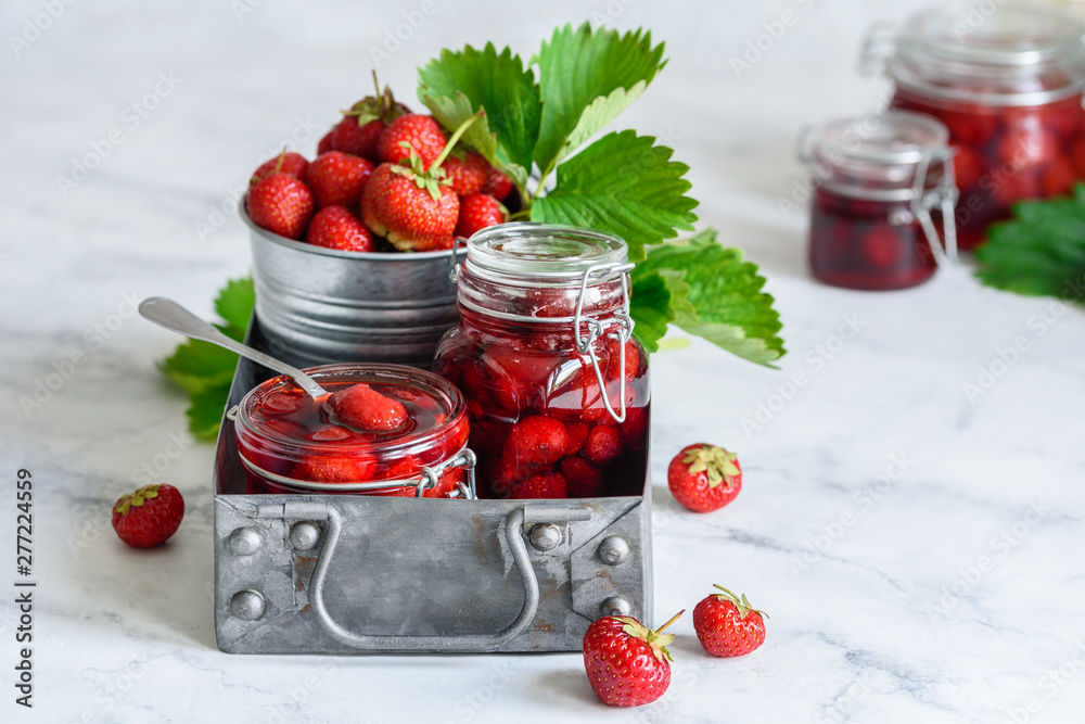Homemade strawberry jam in jars in a metal box on a marble background Homemade strawberry jam in jars in a metal box on a marble background