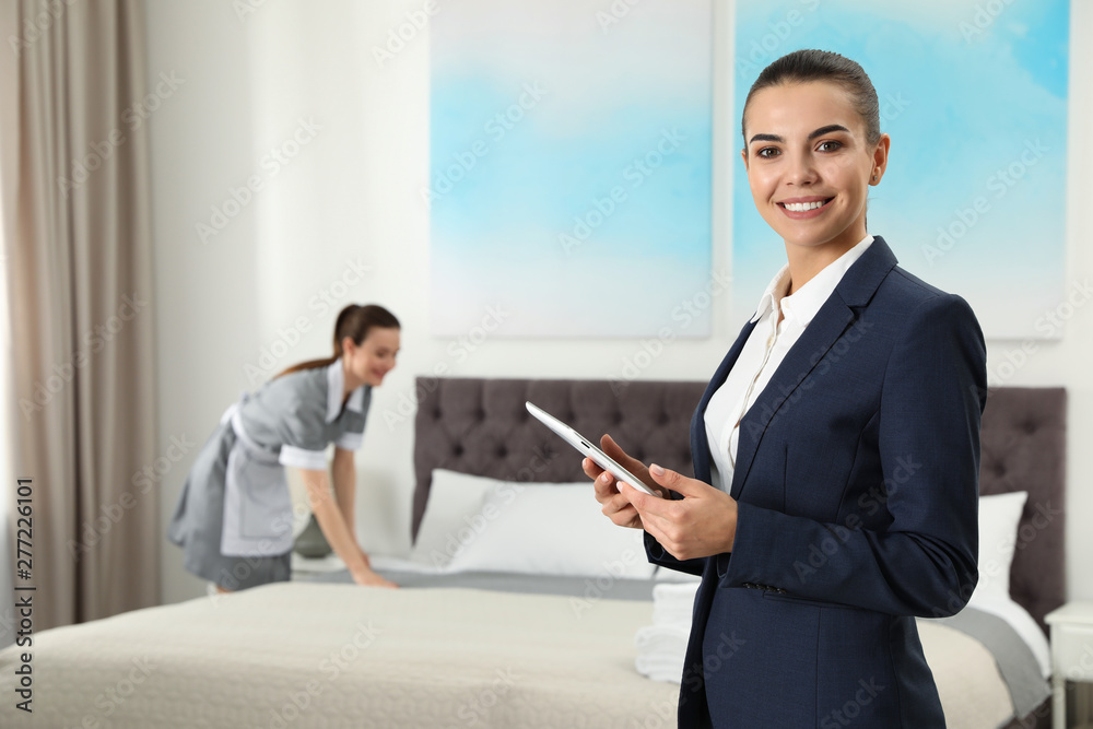 Housekeeping manager with tablet checking maid work in hotel room. Space for text Housekeeping manager with tablet checking maid work in hotel room. Space for text
