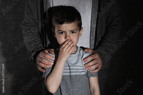 Fotografija Scared little boy and adult man on dark background