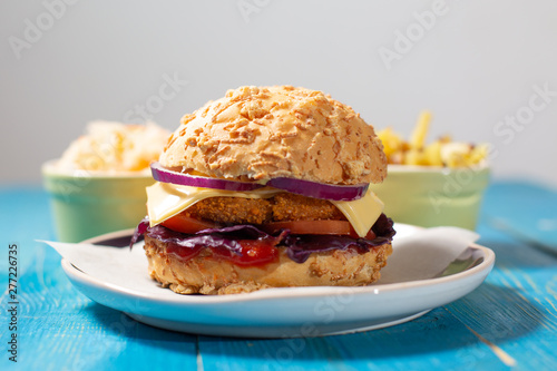 Delicious homemade burger with french fries and salad (coul slow) on a blue table and neutral grey background photo