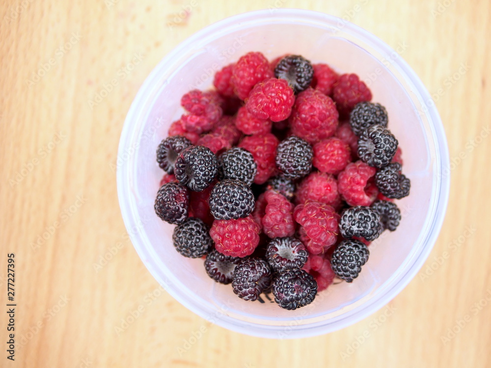 Mix of black and red berries in a plastic container Mix of black and red berries in a plastic container