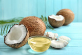 Bowl of natural organic oil and coconuts on blue wooden table, closeup