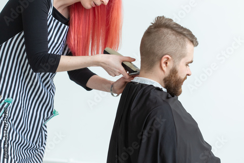Hairdresser, hairstylist and barber shop concept - woman hairstylist cutting a bearded man © satura_