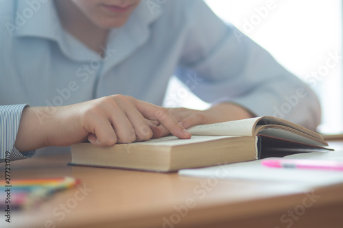 Student sitting at a Desk and reading a book.