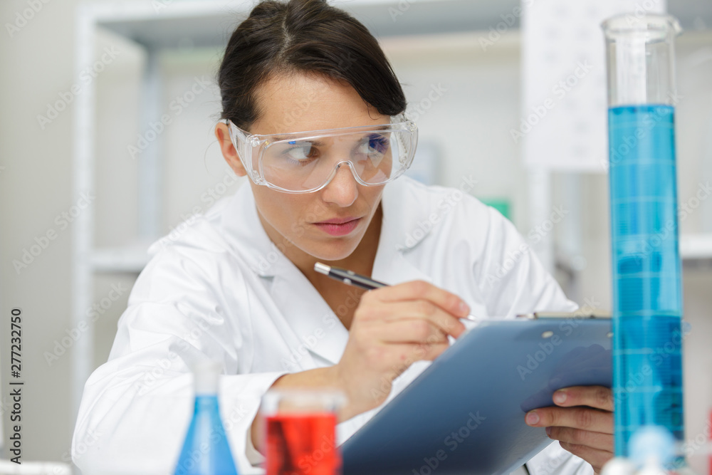 woman writing notes in lab woman writing notes in lab