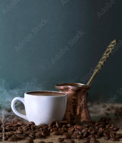 Traditional Turkish coffee and coffee pot with roasted coffe beans around on a sack