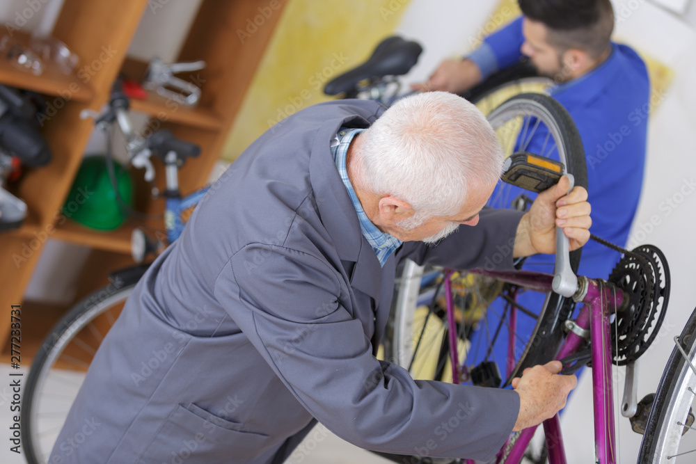 senior handyman fixing bike wheel in his garage