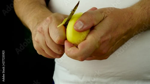 Hands removing skin yellow potato