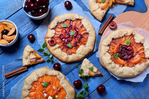 Shortbread galette pies with apricots, cherries and apples topped with mint on the blue wooden table