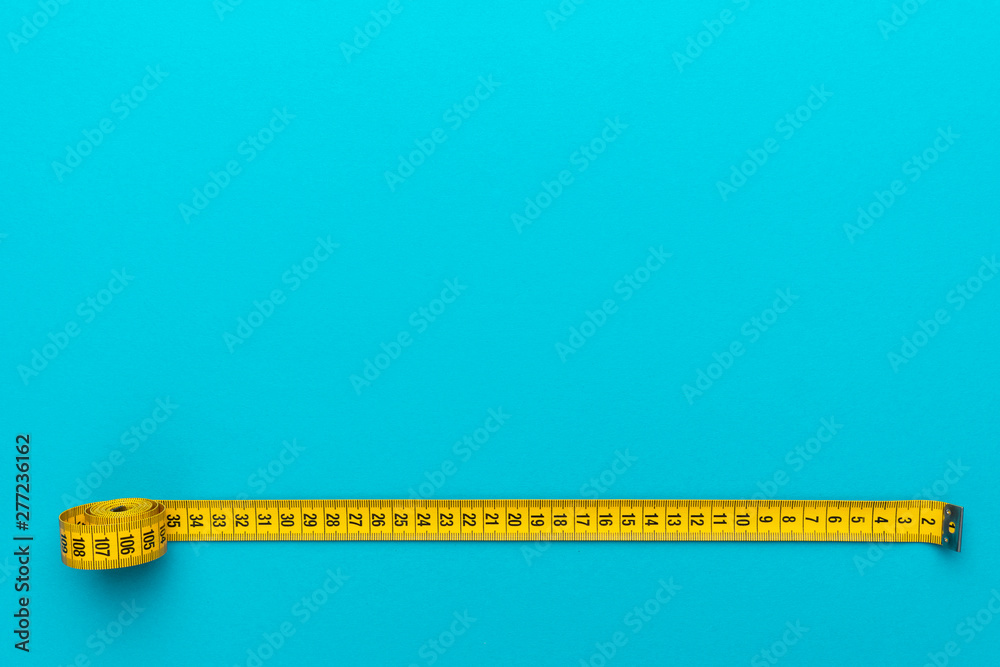 Top view of yellow soft measuring tape. Minimalist flat lay image