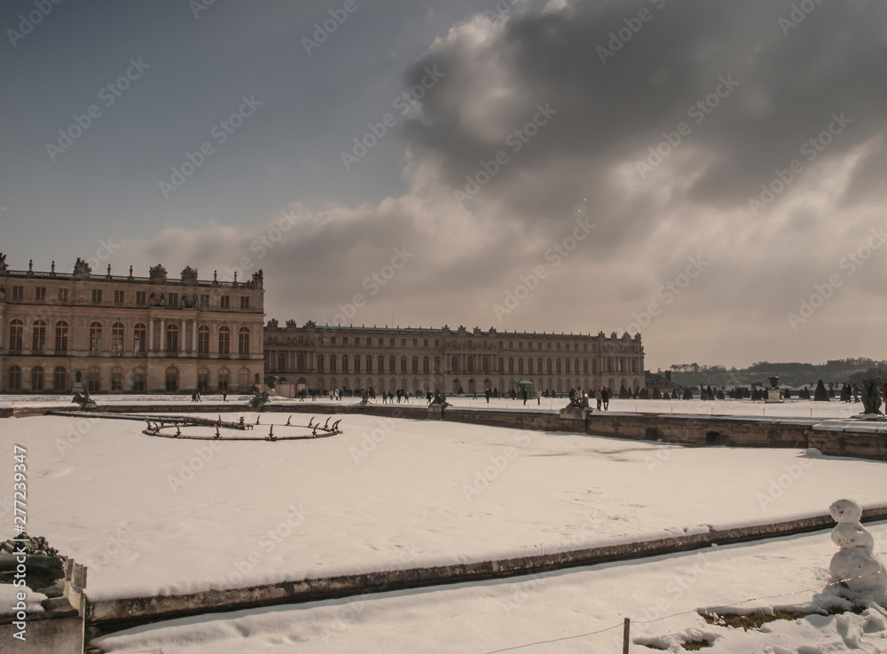 garden sculptures and pond in front of the royal residence at Versailles near Paris in France in winter scenery