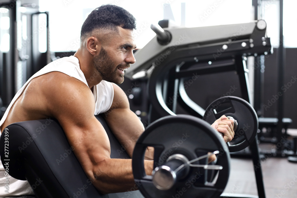Fit and muscular man lifting heavy barbell weight using bench at the gym. Fit and muscular man lifting heavy barbell weight using bench at the gym.