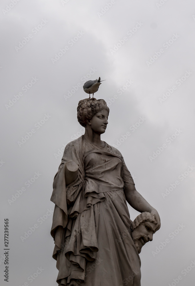 Fototapeta premium a bird on the head of one of the figures in a park in Paris,