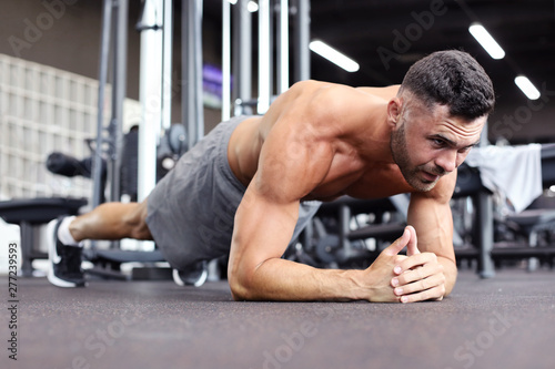 Portrait of a fitness man doing planking exercise in gym.