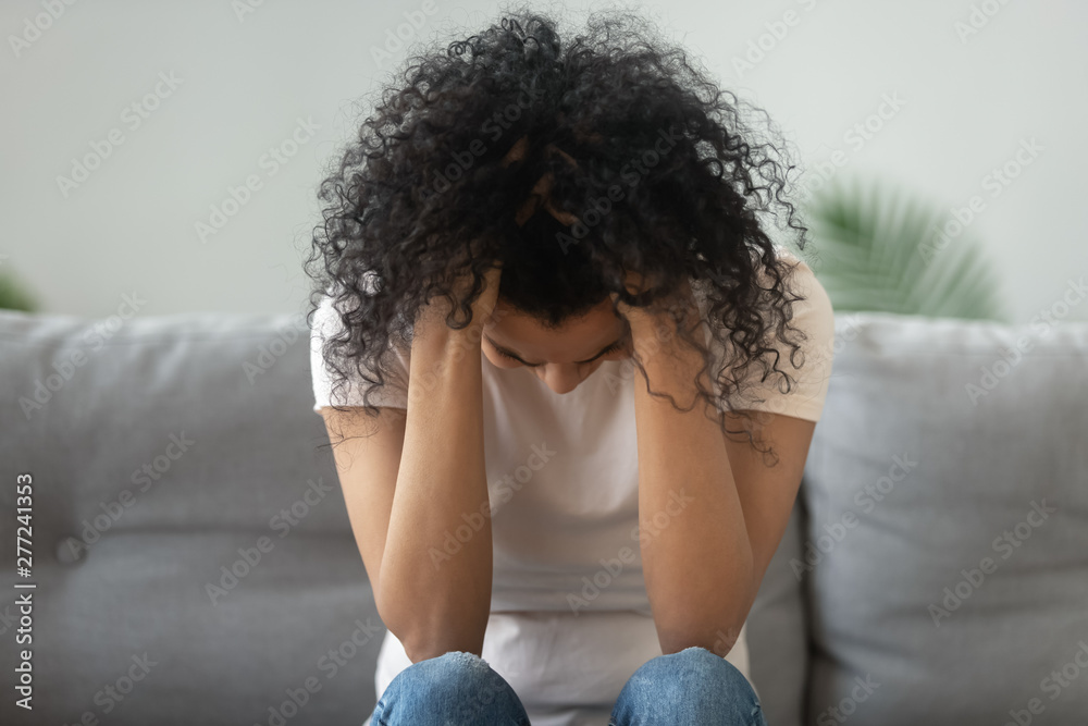 Miserable black woman holding head in hands suffer from grief