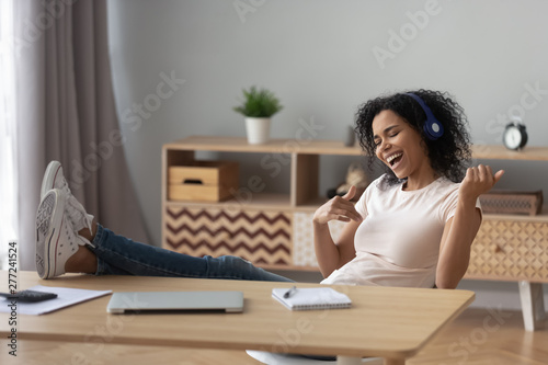 Happy african woman wear headphones playing guitar relaxing after work