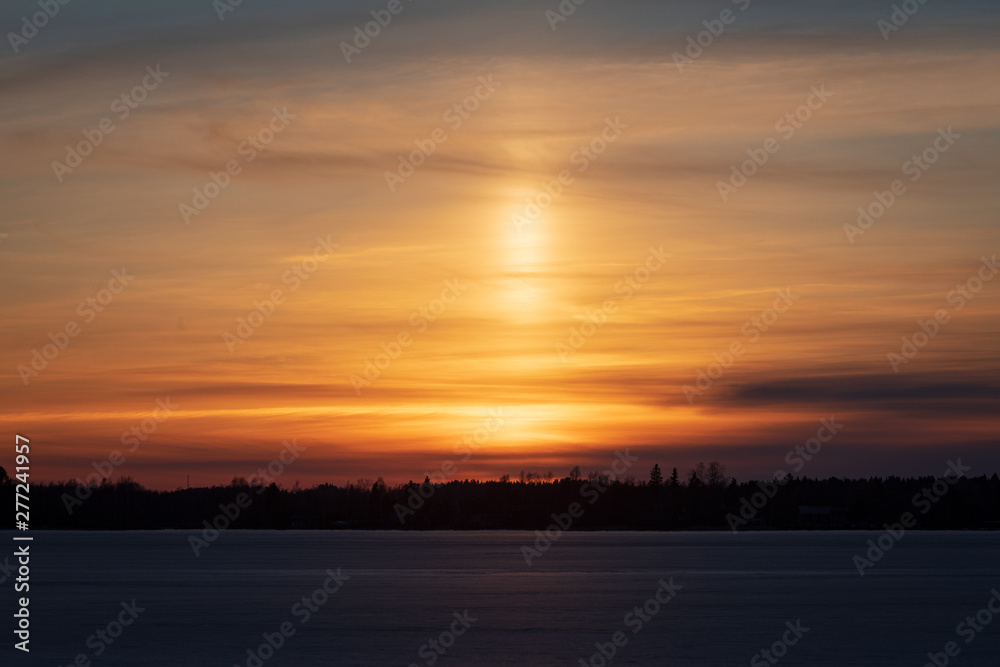 Light pillar in colorful sunset clouds