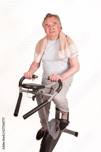 Happy Senior with exercise bike isolated on white