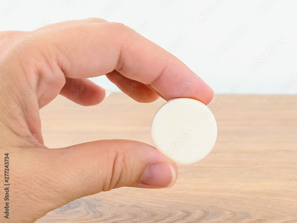 Woman hand holding large pill of soluble effervescent vitamin. Vitamins and nutritional supplements. Health care and medical.