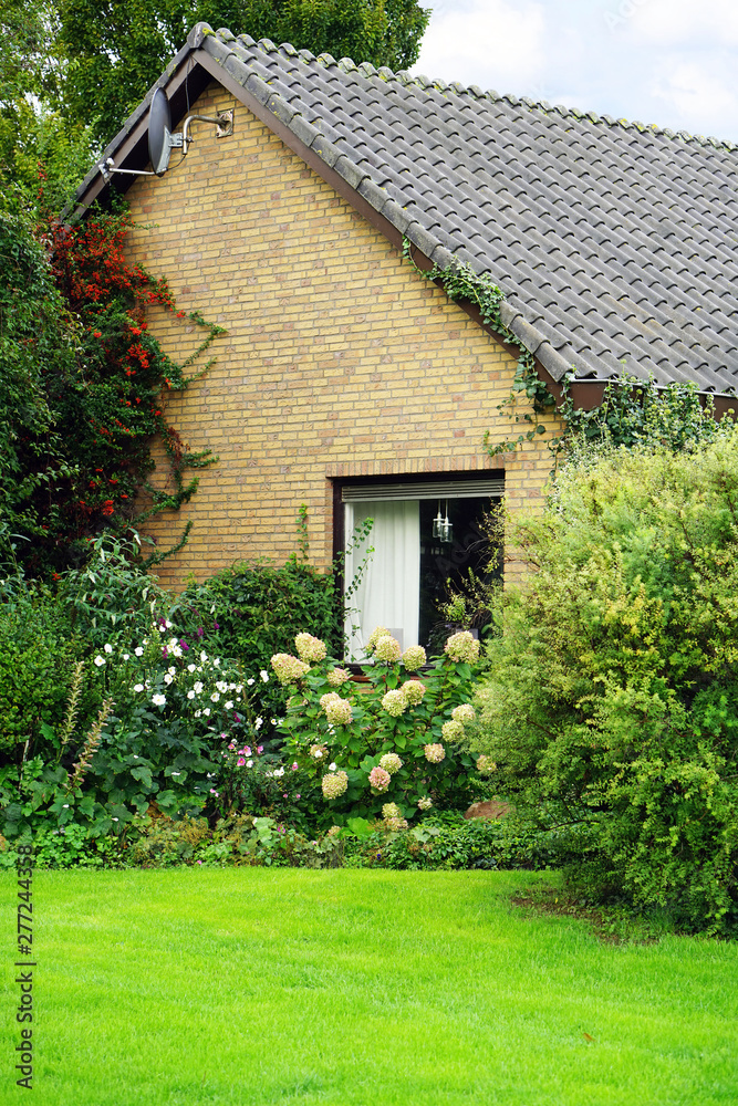 Traditional Dutch house in Netherlands. Beautiful Dutch Scene with a fragment of a brick house and home green garden. Europe
