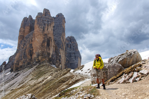Dad with small child in a backpack walks along snow-covered dolomites, Italy.