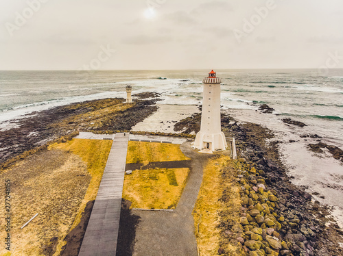 Old lighthouse White on the hill There are stone stairs around the area filled with brown hay. There is a blue sky in the background.Landscape of Iceland. photo