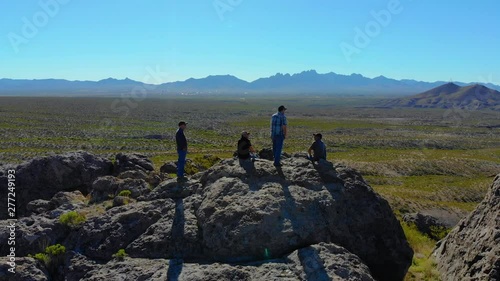 Hikers Enjoy View On Top Pull Back Aerial. aerial view pulling away from people on top of a rock formation in the middle of southwest desert scene photo