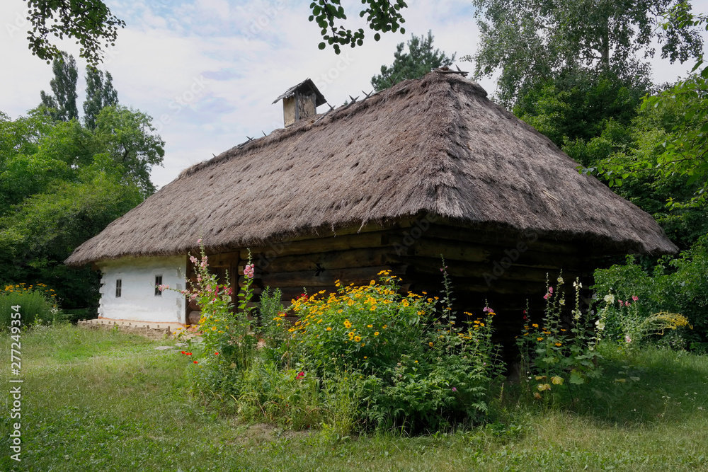 Old Ukrainian house. Ukrainian hut of the nineteenth century. Summer landscape, flowers in front of the house, sunlight. Village Pirogovo. Old Ukrainian house. Ukrainian hut of the nineteenth century. Summer landscape, flowers in front of the house, sunlight. Village Pirogovo.