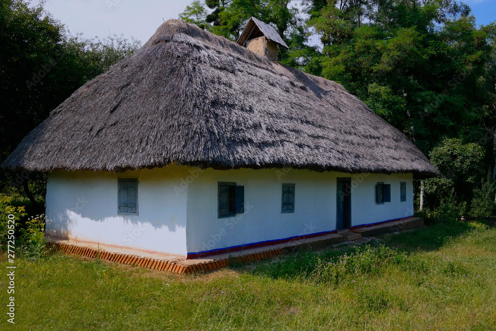 Old Ukrainian house. Ukrainian hut of the nineteenth century. Summer landscape, flowers in front of the house, sunlight. Village Pirogovo. Old Ukrainian house. Ukrainian hut of the nineteenth century. Summer landscape, flowers in front of the house, sunlight. Village Pirogovo.
