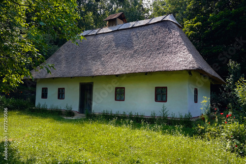 Old Ukrainian house. Ukrainian hut of the nineteenth century. Summer landscape, flowers in front of the house, sunlight. Village Pirogovo.