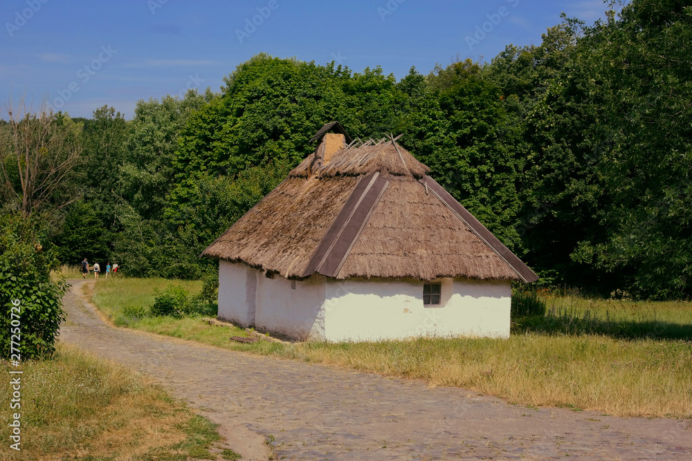 Old Ukrainian house. Ukrainian hut of the nineteenth century. Summer landscape, flowers in front of the house, sunlight. Village Pirogovo.
