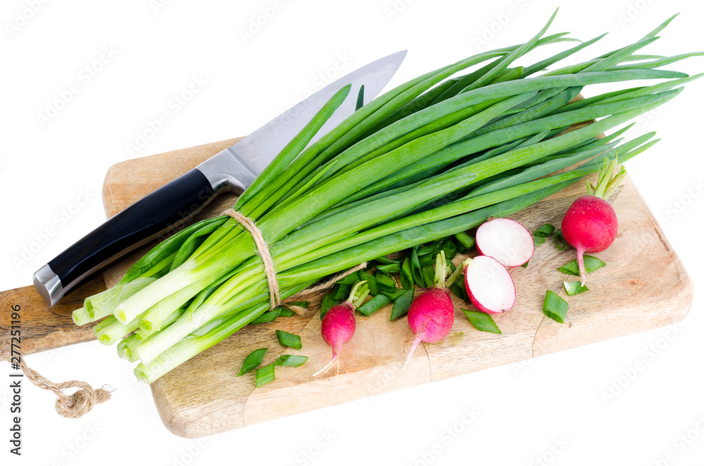 Fresh green onions, red radish on cutting board. 