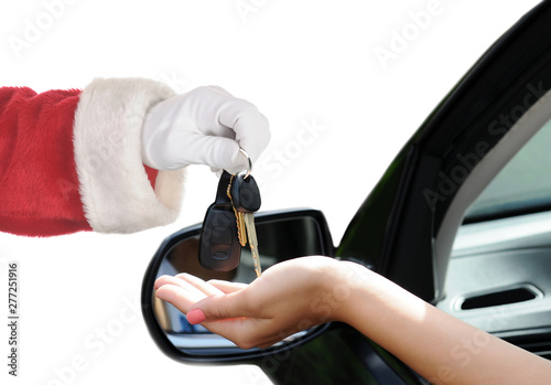 Santa Claus handing over the keys to a new car.