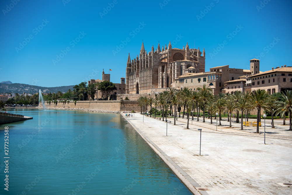 Majorca 2019: Cathedral La Seu of Palma de Mallorca on a sunny summer day with blue sky. Image composition with lake and square with street lamps in the foreground