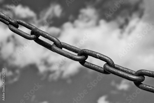 old rusty Chain against cloudy sky. Black and white image