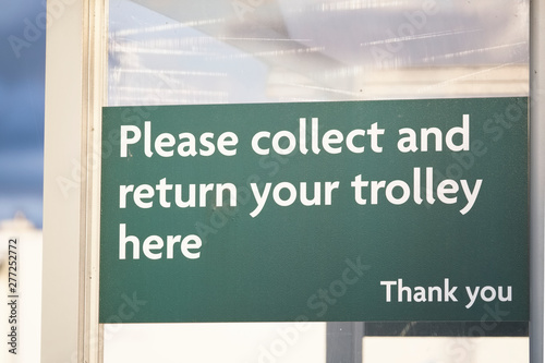 Collect and return trolley sign at supermarket shop shelter store