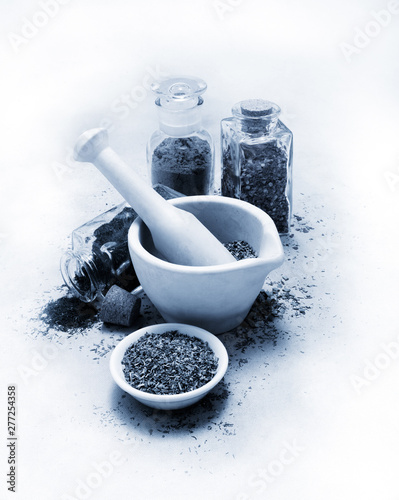 Vintage black and white mortar and pestle with spices and herbs on white canvas table cloth