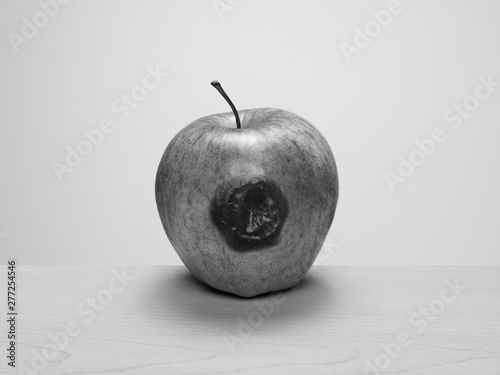 Rotten to the core, bruised apple on wood table