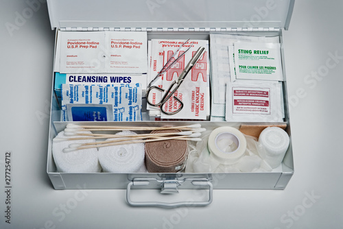 First aid kit packed with medical supplies on grey background