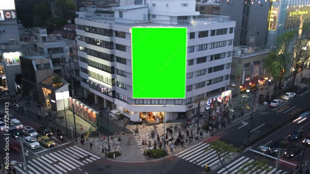 Large billboard with a green screen, on the modern building, busy crossroad with neon lights, timelapse of traffic, Tokyo, Japan