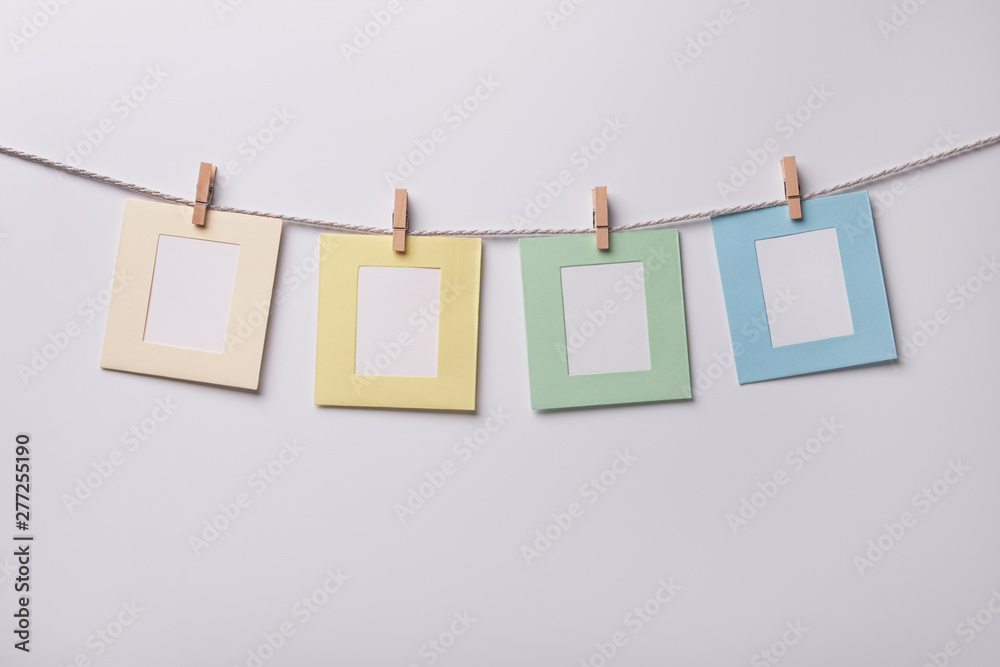 Four multicolored paper photo frames hanging on the rope on white background Four multicolored paper photo frames hanging on the rope on white background