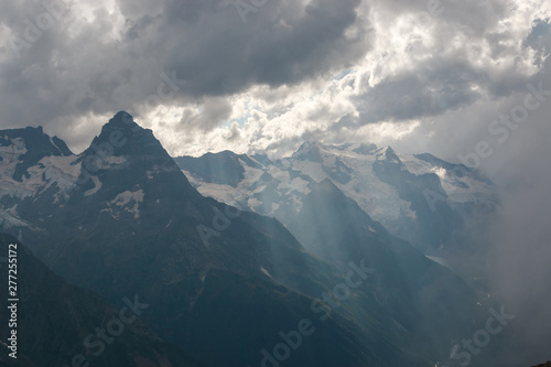 Panorama of misty mountains scene with dramatic sky in national park of Dombay