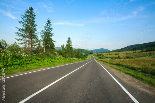 Empty asphalt road in Carpathian mountains among forests and fields